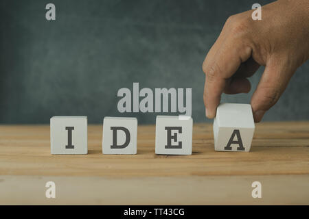 Creative e concetto di successo, mettendo mano cubo di legno blocco con parola idea su un tavolo di legno. Foto Stock