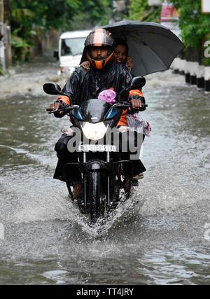 Guwahati, Assam, India. Giugno 14, 2019. Pendolari wade attraverso una strada saturo di acqua dopo la pioggia pesante di Guwahati, Assam, India il Venerdì, 14 giugno 2019. Credito: David Talukdar Alamy Live News Foto Stock