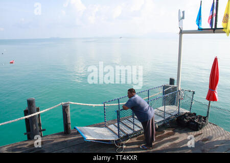 Ko Phangan, Tailandia - 23 Aprile 2013: un uomo attendere sul Thong Sala molo per i traghetti in partenza per la terraferma Thai. Foto Stock