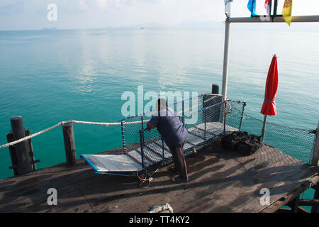 Ko Phangan, Tailandia - 23 Aprile 2013: un uomo attendere sul Thong Sala molo per i traghetti in partenza per la terraferma Thai. Foto Stock