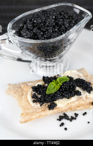 Fetta di pane con burro e sauceboat con caviale su piastra in primo piano Foto Stock