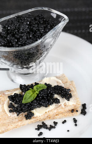 Fetta di pane con burro e sauceboat con caviale su piastra in primo piano Foto Stock