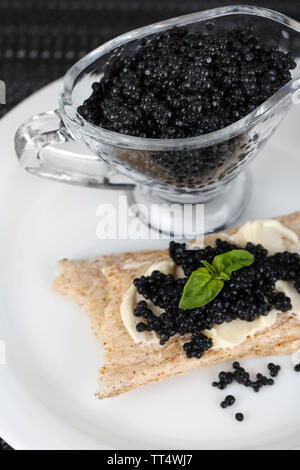 Fetta di pane con burro e sauceboat con caviale su piastra in primo piano Foto Stock