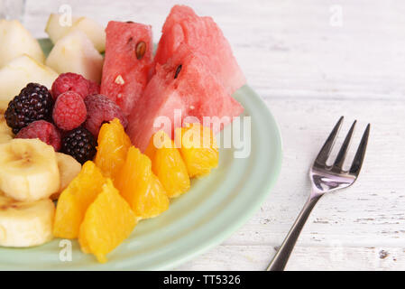 Fette di frutta e bacche su piastra su un tavolo di legno Foto Stock