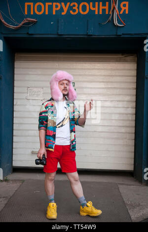 Mosca, Russia - Giugno 12, 2019: un giovane uomo in un abbonamento a Motley di stile Hawaiiano, camicia bianca T-shirt rossa, pantaloncini corti e una rosa cappello di pelliccia con una telecamera sorge in fro Foto Stock