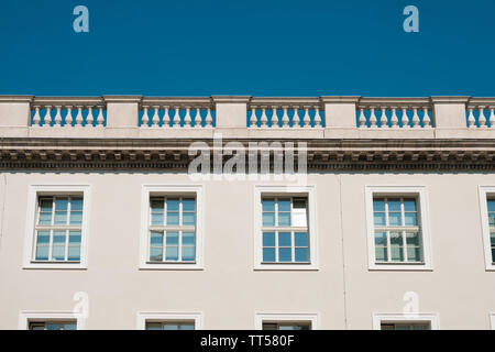 Parte superiore della facciata di edificio con terrazza balaustrata e cielo blu - Foto Stock