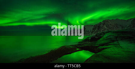 Panorama di aurora su Tugeneset costa rocciosa con le montagne sullo sfondo, Senja, Norvegia Foto Stock