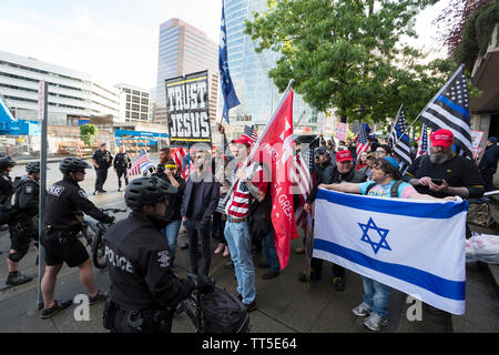 Manifestanti chant contro sost. Ilhan Omar come polizia area di utilizzare le loro biciclette come una barricata tra loro e counterprotesters a Bellevue, Washington, Sabato 25 Maggio, 2019. I patrioti di Washington group lead la protesta contro il rappresentante che era un rivestimento padiglione CAIR-WA Ramadan raccolta fondi. Foto Stock