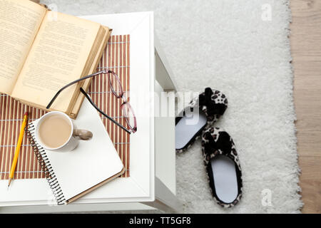 Ancora i dettagli di vita, una tazza di caffè, libro e i bicchieri sul tavolo, su home background interni Foto Stock