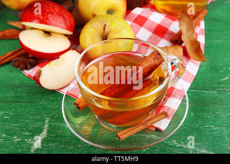 Composizione del sidro di mela con bastoncini di cannella, mele fresche e foglie di autunno su sfondo di legno Foto Stock