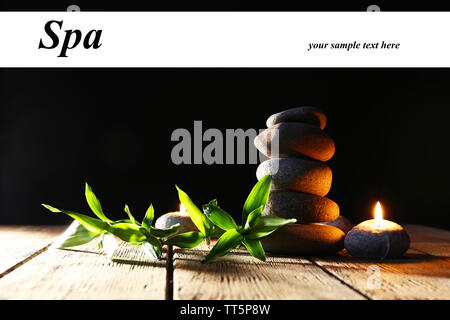 Spa pietre, candele sul tavolo di legno su sfondo scuro Foto Stock