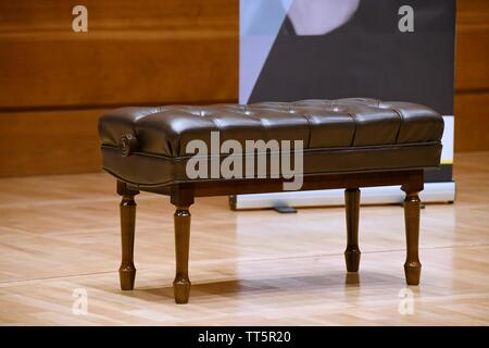 In legno marrone sgabello pianoforte sul palcoscenico in legno in concert hall Foto Stock