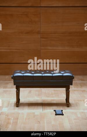 In legno marrone sgabello pianoforte sul palcoscenico in legno in concert hall Foto Stock