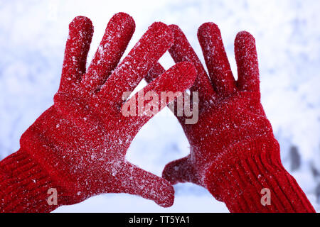 Donna con le mani in mano in rosso guanti in inverno sfondo naturale Foto Stock