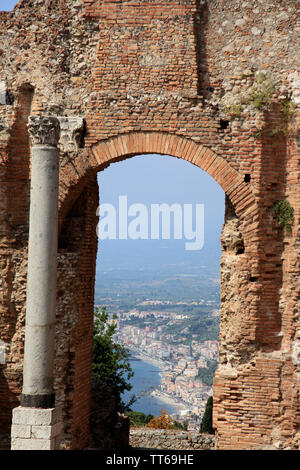 Guardando attraverso un arco del Teatro Greco verso Giardini Naxos e sul Monte Etna nella distanza in Taormina Sicilia in Italia Foto Stock