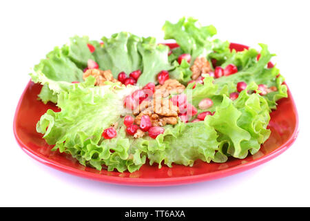 Insalata fresca con verdi, granato e spezie sulla piastra isolata su bianco Foto Stock