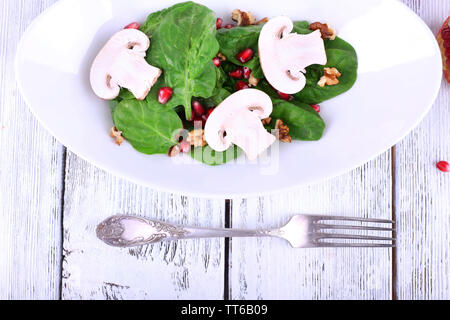 Insalata fresca con verdi, granato e spezie su lastra sul tavolo di close-up Foto Stock