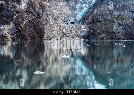 Acqua riflessioni di rocce e di un ghiacciaio attraverso il Parco Nazionale di Glacier Bay in Alaska, con pezzi di ghiaccio galleggianti intorno. Natura astratta del design. Foto Stock