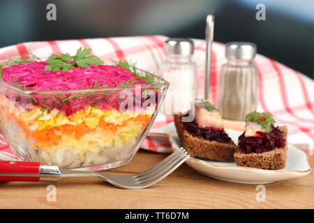 Russo insalata di aringhe nella ciotola di vetro sul tavolo di legno, su sfondo lucido Foto Stock