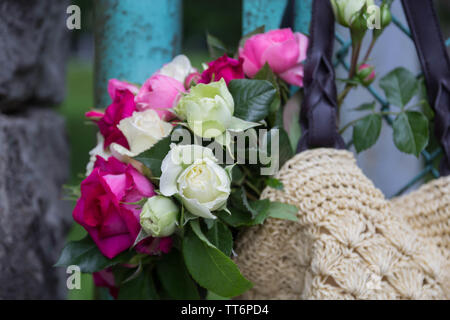 Bouquet di fragrante rosa Inglese e rose bianche in una borsa di rafia appesa alla recinzione Foto Stock