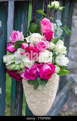 Bouquet di fragrante rosa Inglese e rose bianche in una borsa di rafia appesa alla recinzione Foto Stock