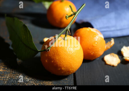 Succosa mature tangerini con foglie su un tavolo di legno Foto Stock