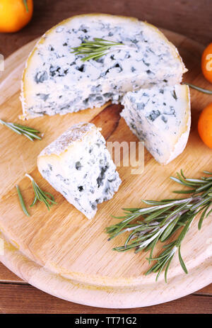 Formaggio blu con rametti di rosmarino e le arance a bordo e tavolo in legno sfondo Foto Stock