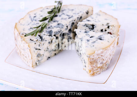 Formaggio blu con rametti di rosmarino su piastra e in legno di colore di sfondo della tabella Foto Stock