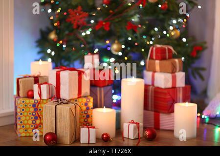 Pila di scatole presenti sotto albero di Natale sul pavimento in legno, in interni Foto Stock