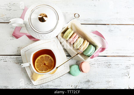 Amaretti colorati con tazza di tè su sfondo di legno Foto Stock