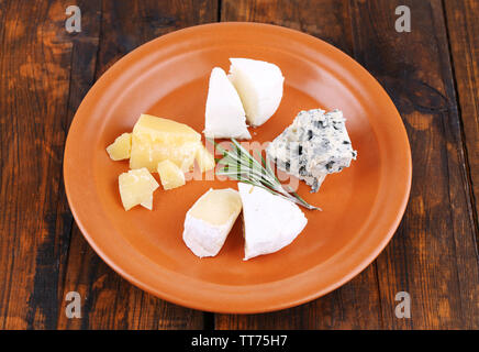 Fette di diverso tipo di formaggio sulla piastra su un tavolo di legno sfondo Foto Stock