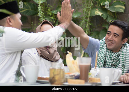 Due man mano avente toast al tavolo da pranzo durante la pausa del pranzo e cena durante il ramadan celebrazione, rompere il digiuno Foto Stock