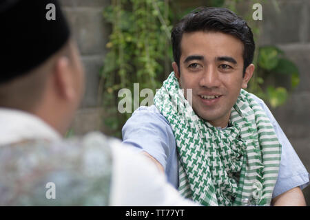 Due uomo avente il tremolio delle mani al tavolo da pranzo durante la pausa del pranzo e cena durante il ramadan celebrazione, rompere il digiuno Foto Stock