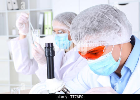 Maschio e femmina di scienziati mediante microscopio in laboratorio Foto Stock