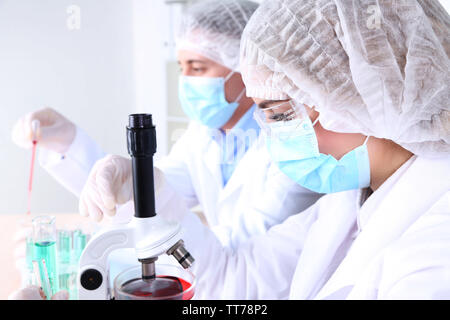 Maschio e femmina di scienziati mediante microscopio in laboratorio Foto Stock