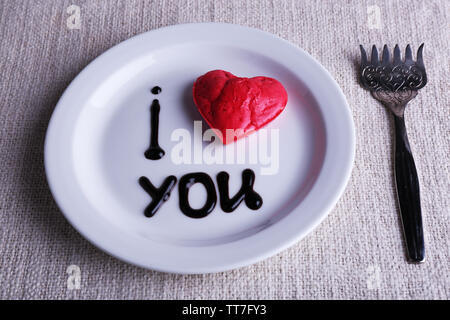 Cookie a forma di cuore sulla piastra con iscrizione ti amo, sul tovagliolo sfondo Foto Stock
