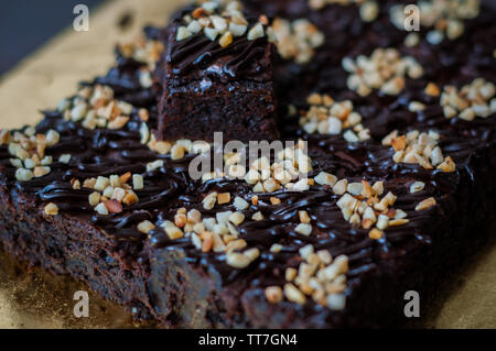 Torta al cioccolato Brownie piazze spruzzata con la cioccolata Nutella e noci. Vista ingrandita, il fuoco selettivo Foto Stock