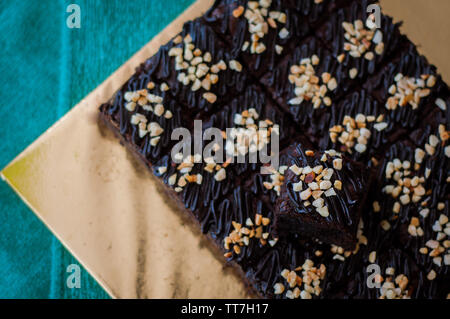 Torta al cioccolato Brownie piazze spruzzata con la cioccolata Nutella e noci. Vista ingrandita, il fuoco selettivo Foto Stock