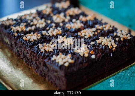 Torta al cioccolato Brownie piazze spruzzata con la cioccolata Nutella e noci. Vista ingrandita, il fuoco selettivo Foto Stock