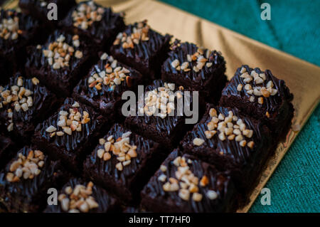 Torta al cioccolato Brownie piazze spruzzata con la cioccolata Nutella e noci. Vista ingrandita, il fuoco selettivo Foto Stock