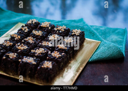 Torta al cioccolato Brownie piazze spruzzata con la cioccolata Nutella e noci. Vista ingrandita, il fuoco selettivo Foto Stock