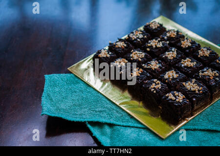 Torta al cioccolato Brownie piazze spruzzata con la cioccolata Nutella e noci. Vista ingrandita, il fuoco selettivo Foto Stock