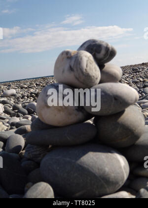 Zen pietre sulla spiaggia. Abstract ciottoli di mare torre closeup. Concetto di pietre equilibrio e armonia stack di ciottoli sulla spiaggia durante il giorno su un sunn Foto Stock