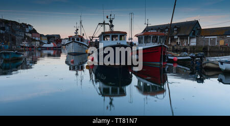 Barche da pesca ormeggiate per la notte e si riflette in un mare calmo, Mevagissey Harbour, Cornwall, Regno Unito. Foto Stock