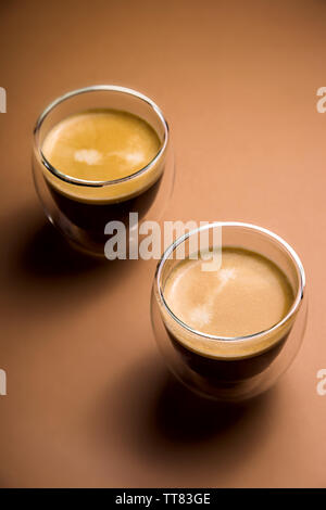 Nero caffè americano in un vetro trasparente con doppio vetro su una posizione neutra di sfondo marrone Foto Stock