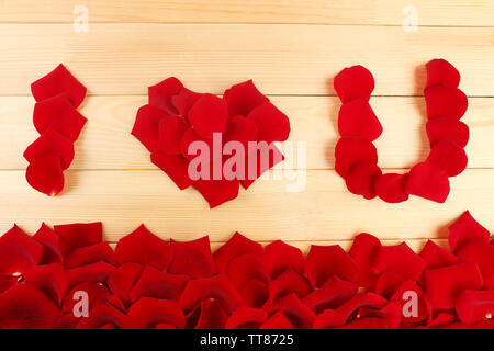 Parole Ti Amo formata da petali di rose su sfondo di legno Foto Stock