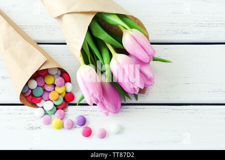 Di un bel colore rosa tulipani in carta con dolci su sfondo di legno Foto Stock