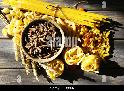 Diversi tipi di pasta su tavole di legno sfondo Foto Stock