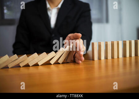 Imprenditore si ferma mano domino capovolta continua nel senso che ostacolavano il fallimento aziendale. Stop Over questo fallimento aziendale concetto. Foto Stock