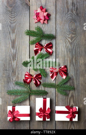 Albero di natale concetto con confezioni regalo, Abete rami, nastri e star su sfondo di legno Foto Stock